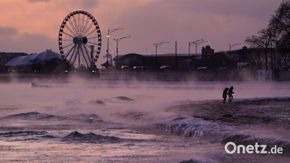 Menschen spazieren in Chicago über einen mit Eis bedeckten Strand am Ufer des Michigansees. Bild: Kiichiro Sato/AP/dpa