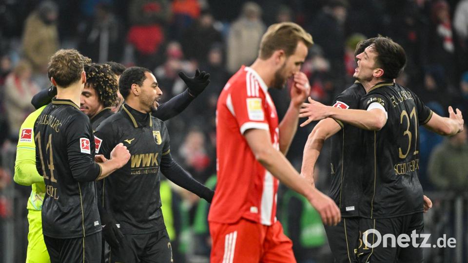 Fußball: Bundesliga, FC Bayern München - FC Augsburg, 19. Spieltag, Allianz Arena. Die Spieler des FC Augsburg jubeln nach Spielende. Davor geht Harry Kane (Bayern München). Das Spiel endete 1:2. Bild: Peter Kneffel/dpa