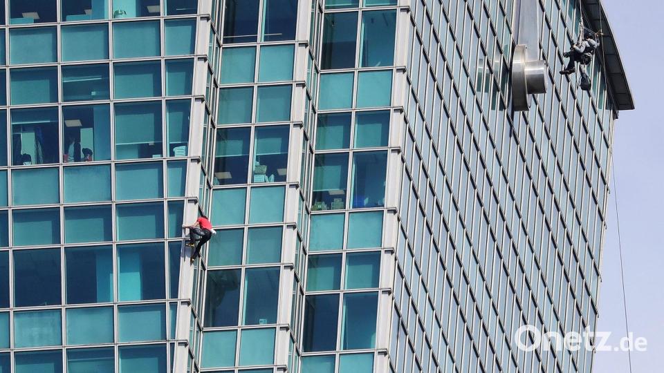 Schaulustige beobachteten Alex Honnold nicht nur vom Boden aus - auch hinter den Bürofenstern wurde der Extremsportler angefeuert. Bild: ChiangYing-ying/AP/dpa