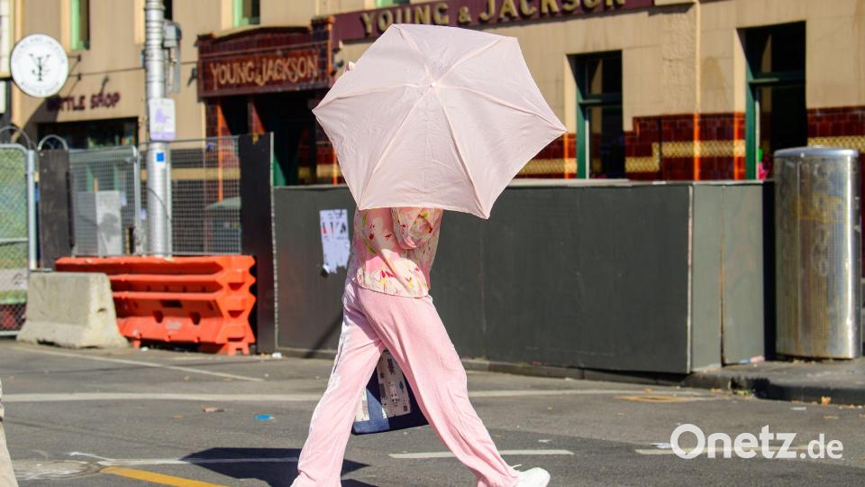 Eine Frau benutzt einen Regenschirm, um sich vor der Sonne zu schützen. Bild: Michael Currie/AAP/dpa