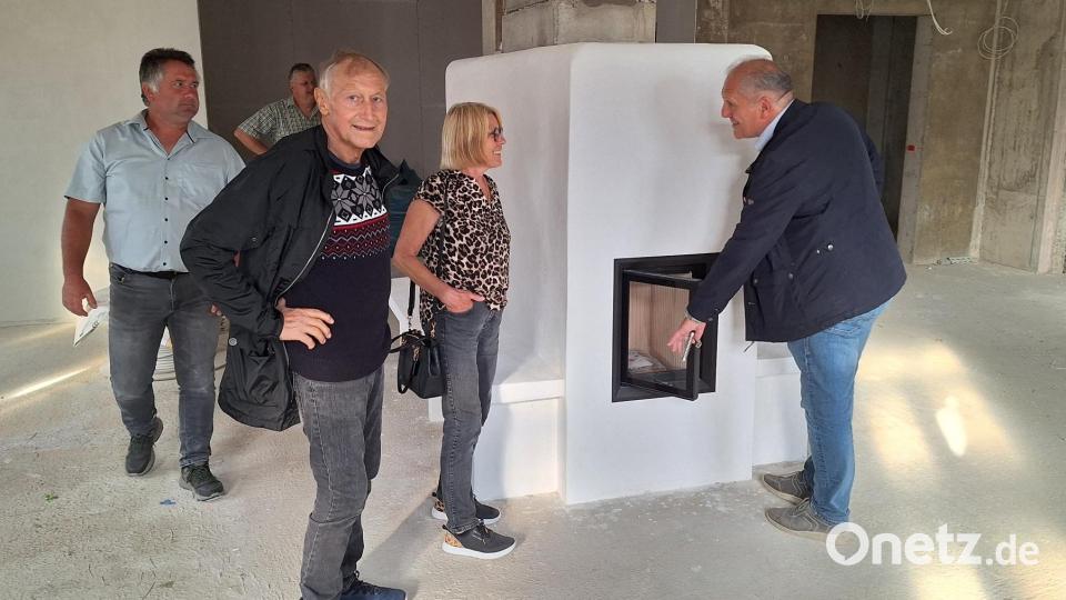 Ein Kachelofen soll in der Gaststube für ein gemütliches Ambiente sorgen. Bürgermeister Werner Prucker (rechts) testet die Ofentür. Bild: fks