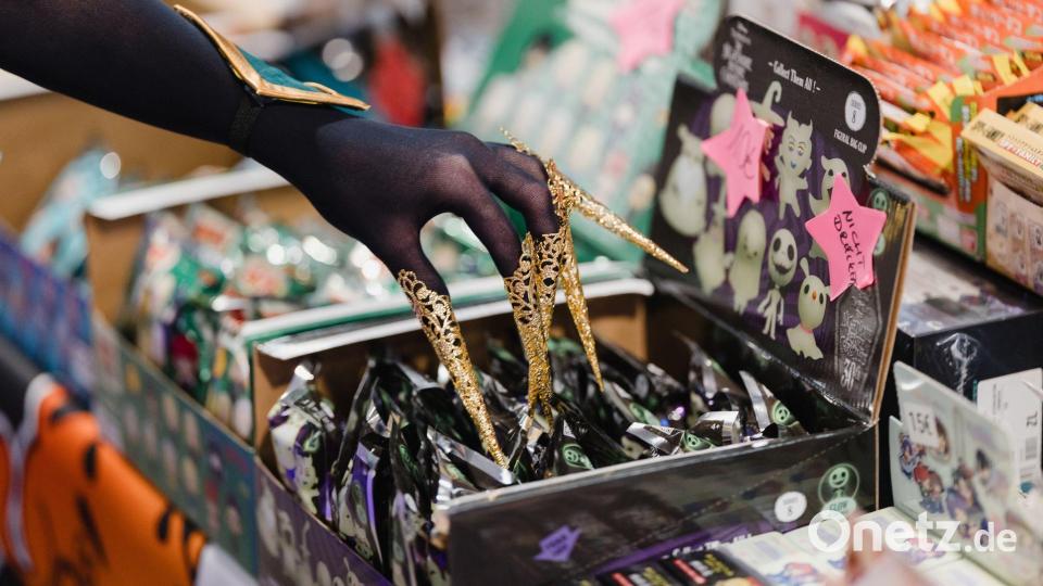 Eine verkleidete Messebesucherin berührt auf der Manga- und Comic-Messe „MAG-C“ ausgestellte Produkte. Bild: Michael Reichel/dpa