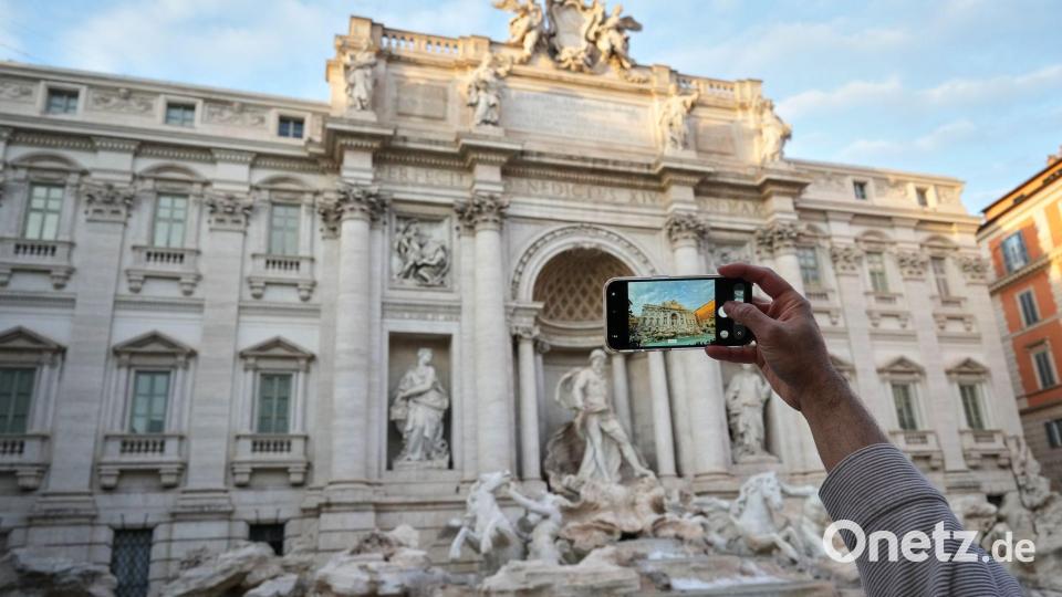 Ein Besucher macht ein Foto des Trevi-Brunnens. (Archivbild) Bild: Andrew Medichini/AP/dpa