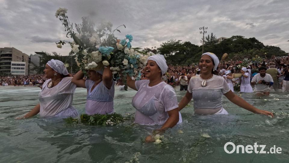 Gläubige werfen Blumen in das Wasser. Bild: Bruna Prado/AP/dpa