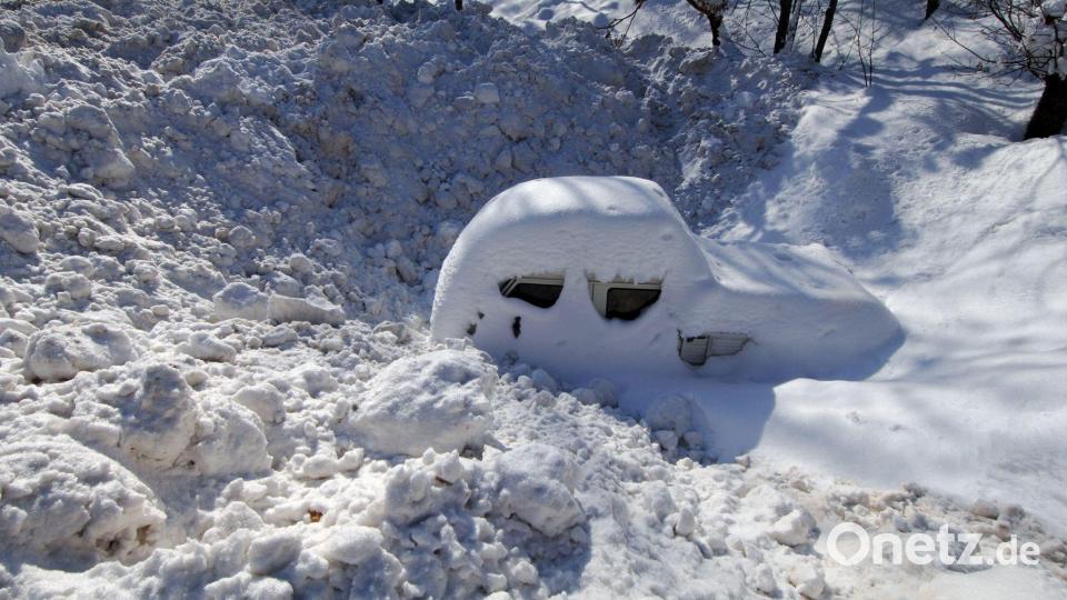 Ein Auto - eingeschneit und umschlossen von Schneemassen - auf einem Parkplatz. (Archivbild) Bild: Armin Weigel/dpa