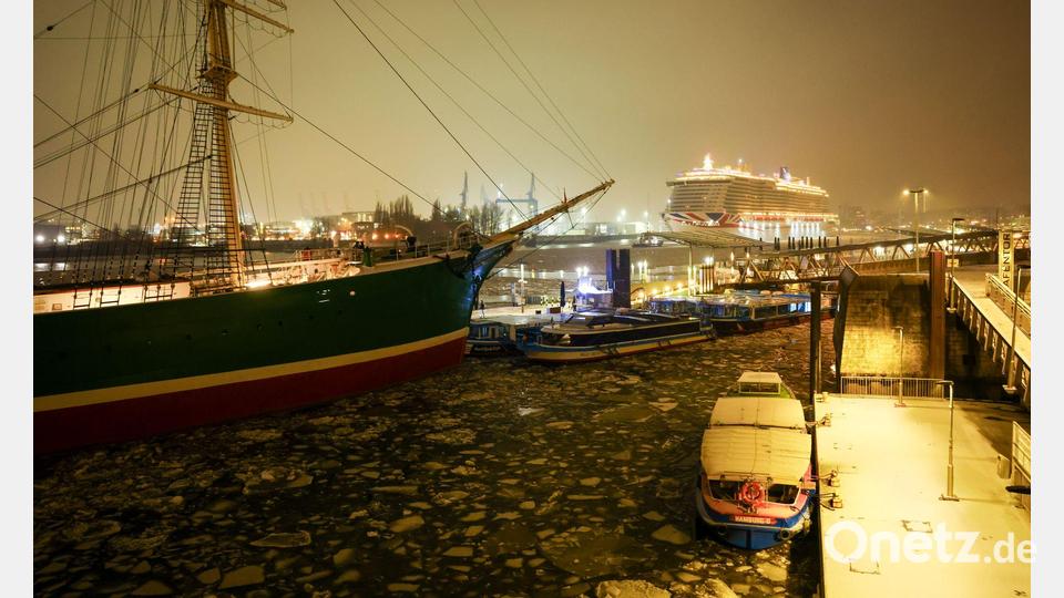 Das Kreuzfahrtschiff Iona (r) des britisch-amerikanischen Kreuzfahrtunternehmens P&amp;O Cruises fährt an den Hamburger Landungsbrücken über die mit kleinen Eisschollen bedeckte Elbe in Richtung eines Kreuzfahrtterminals in der Hafencity. Bild: Christian Charisius/dpa