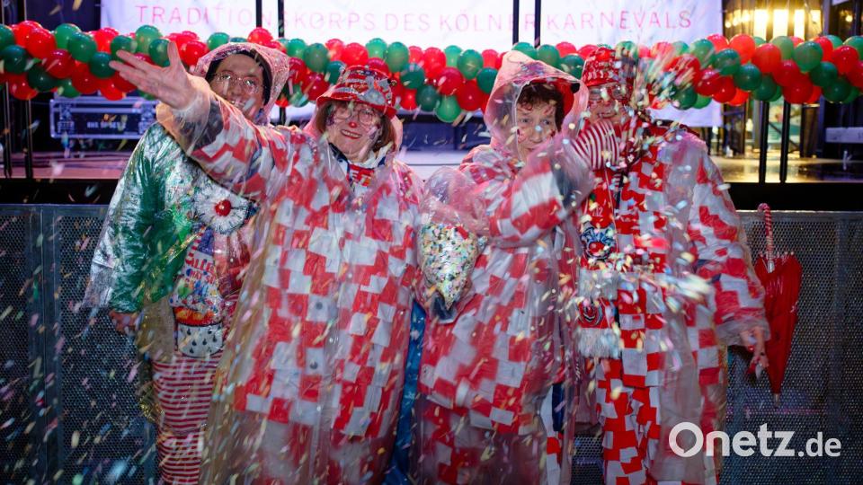 Erste Jecken warten im Regen auf dem Alter Markt an Weiberfastnacht auf den Beginn des Straßenkarnevals in Köln. Bild: Henning Kaiser/dpa