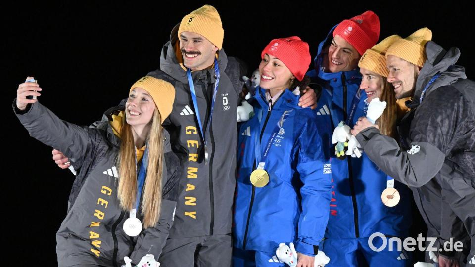 Tabitha Stoecker (Großbritannien) und Matt Weston (Großbritannien, beide M) posieren bei der Siegerehrung ihren Goldmedaillen nach dem Skeleton-Team-Wettbewerb neben Susanne Kreher (Deutschland, l) und Axel Jungk (Deutschland, 2.v.l.) mit der Silbermedaille und Jacqueline Pfeifer (Deutschland, 2.v.r.) und Christopher Grotheer (Deutschland) mit der Bronzemedaille bei den Olympischen Winterspielen Mailand Cortina 2026. Bild: Robert Michael/dpa