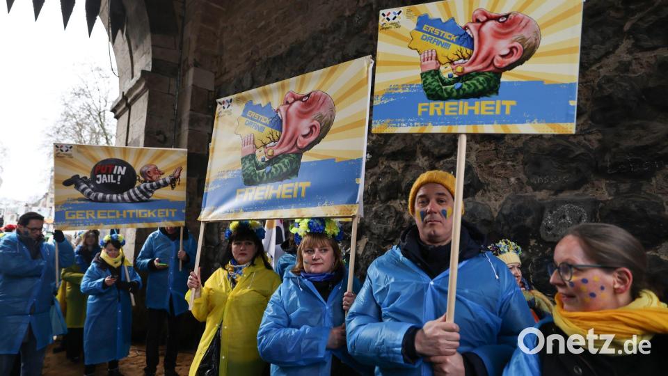 Mitglieder des ukrainischen Hilfsvereins Blau-Gelbes Kreuz halten im Kölner Rosenmontagszug Plakate mit früheren Putin-Darstellungen aus den Zügen in Köln und Düsseldorf hoch. Bild: Oliver Berg/dpa