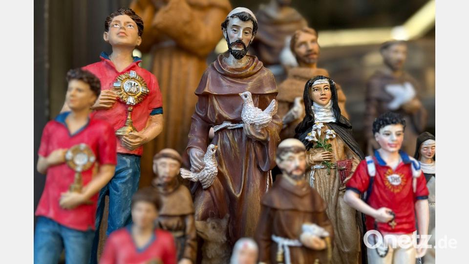 Figuren des alten und des neuen Heiligen stehen in Souvenirshops nebeneinander. (Archivbild) Bild: Christoph Sator/dpa