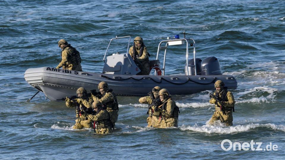 Taucher machen den Anfang und steigen aus dem Wasser auf den schneebedeckten Strand, um den Küstenabschnitt zu sichern. Bild: Fabian Bimmer/Reuters/Pool/dpa