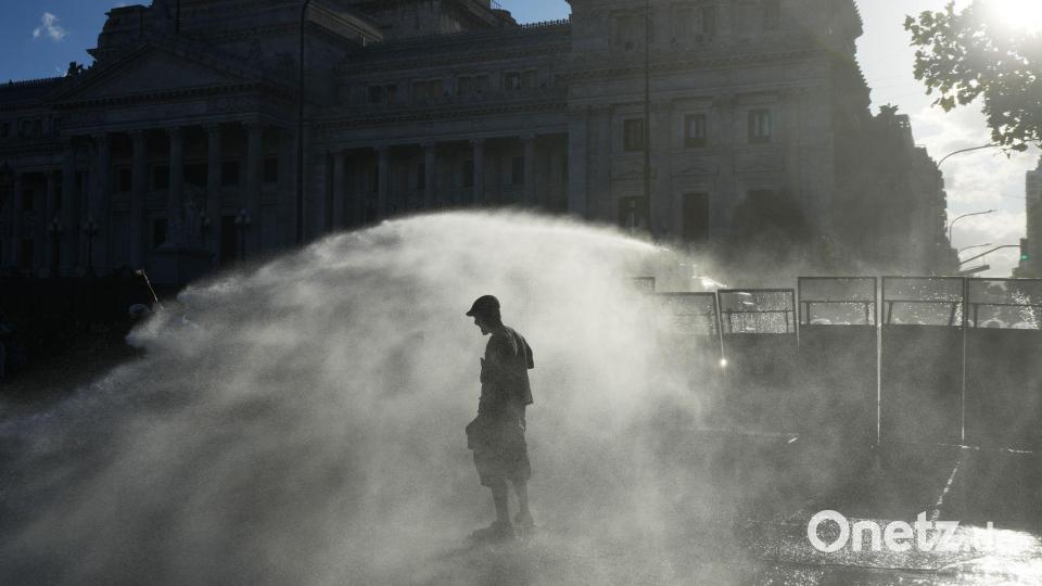 Demonstranten werden in Buenos Aires von einem Wasserwerfer der Polizei besprüht. Bild: Rodrigo Abd/AP/dpa