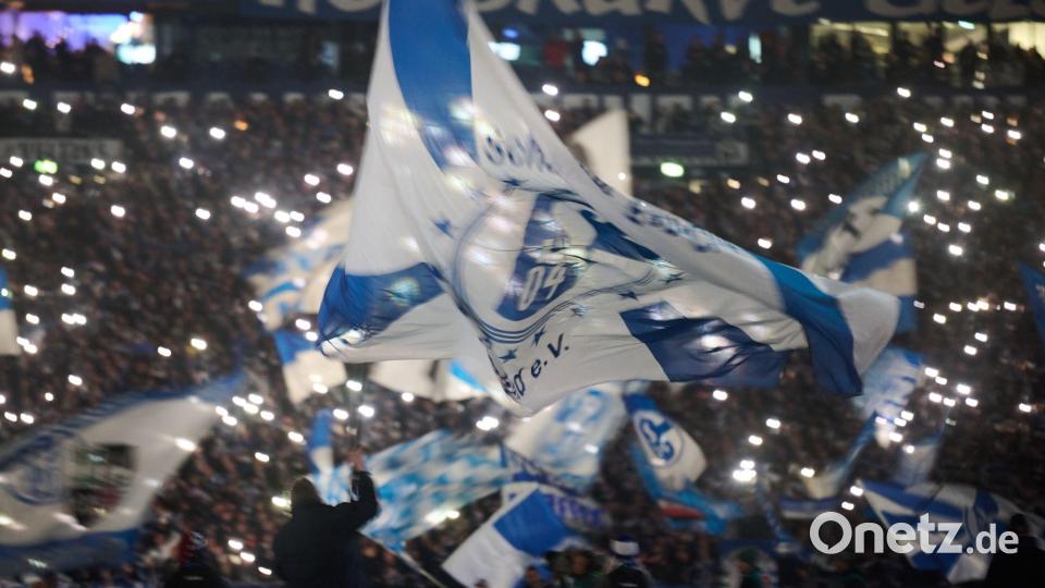 Eine Schalker Vereinsfahne weht vor dem Spiel gegen den 1. FC Magdeburg vor den Lichtern von Smartphones. Bild: Bernd Thissen/dpa