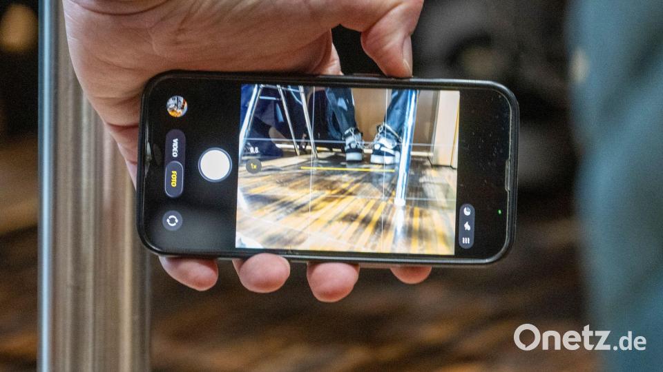 Eine Person fotografiert mit einem Smartphone die Fußfesseln, die der Angeklagte Halid S. im Gerichtssaal tragen muss. Bild: Stefan Puchner/dpa