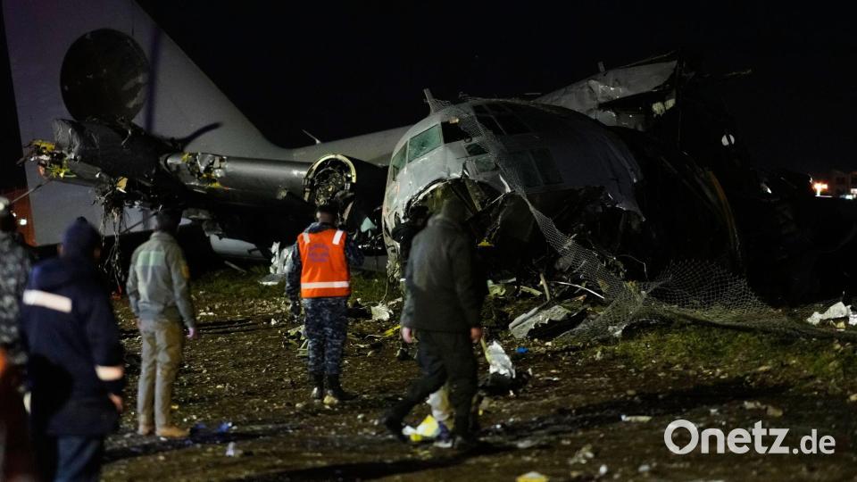 Menschen laufen an der Stelle vorbei, an der ein Flugzeug auf einer Autobahn in El Alto, Bolivien, abgestürzt ist. Bild: Juan Karita/AP/dpa