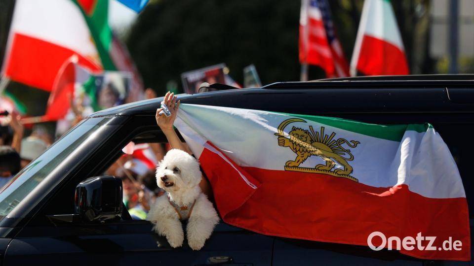 Ein Autofahrer befestigt eine iranische Flagge an einem Fenster. Bild: Caroline Brehman/AP/dpa