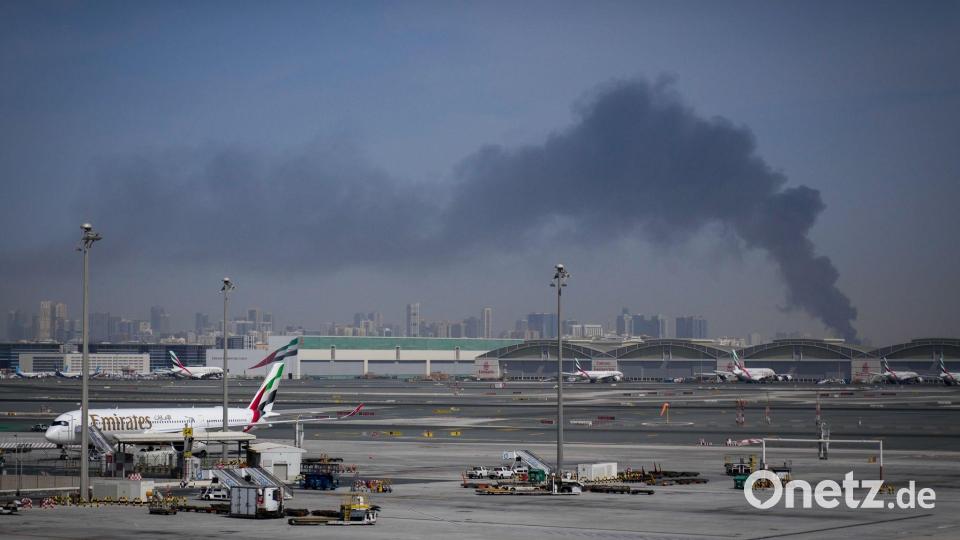 Eine Rauchwolke im Hintergrund, während Flugzeuge auf dem geschlossenen Dubai International Airport geparkt sind. Bild: Altaf Qadri/AP/dpa