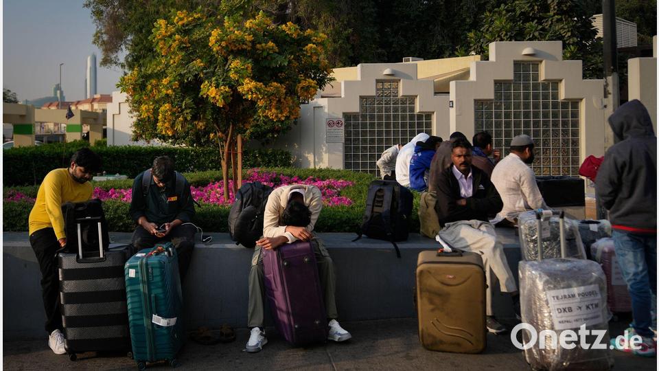 Gestrandete Passagiere warten auf dem Flughafenparkplatz in Dubai. Bild: Altaf Qadri/AP/dpa