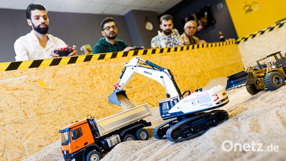 Gründer Siymo Othman (links) steuert mit Freunden kleine Bagger, Radlader und Lastwagen in seinem neu eröffneten Bagger-Café. Es soll das erste dieser Art in Deutschland sein. Bild: Moritz Frankenberg/dpa