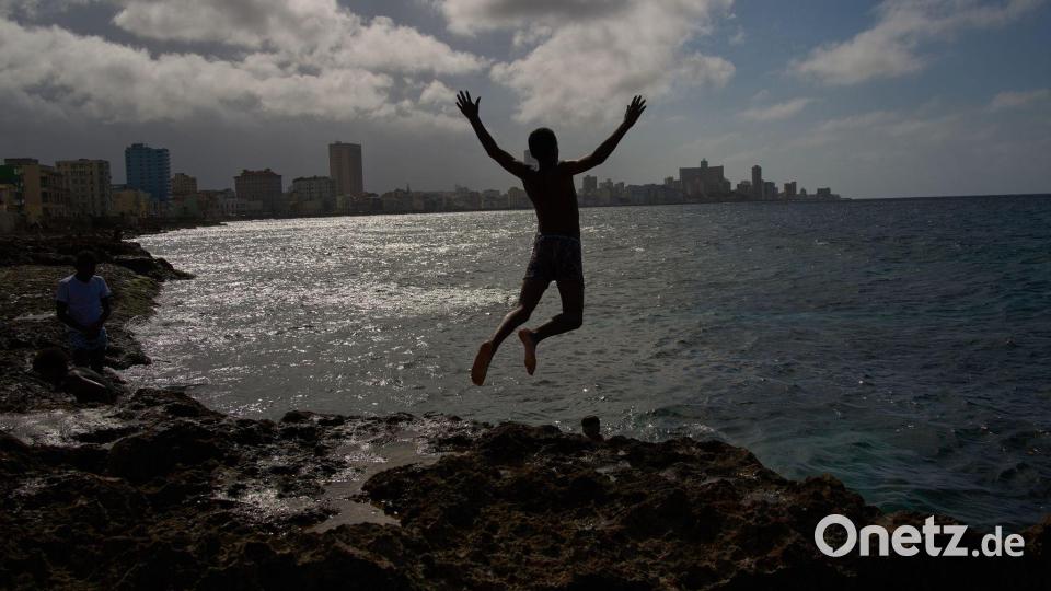 Ein Junge springt ins Meer, auch wenn der Strom in Land ausgefallen ist. Bild: Ramon Espinosa/AP/dpa