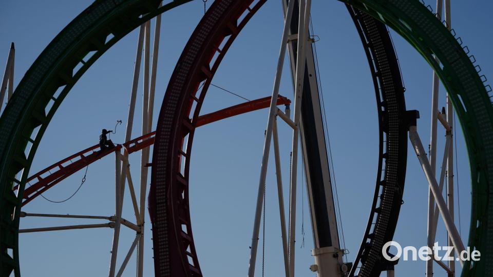 Eine Höhenkletterin nimmt in luftiger Höhe während der Aufbauarbeiten des Frühlingsdoms eine Schiene der Achterbahn auf dem Heiligengeistfeld in Hamburg entgegen. Bild: Marcus Brandt/dpa