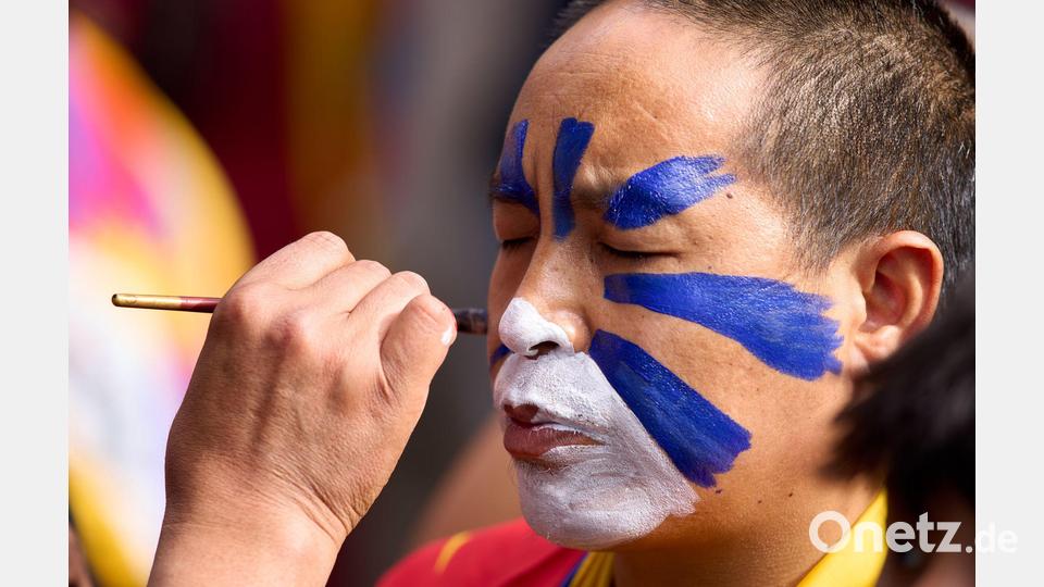 Jahrestag des Aufstandes gegen die chinesische Besatzung in Tibet: Ein tibetischer Mönch im Exil lässt sein Gesicht in einem Tempel in Indien in den tibetischen Farben bemalen. Bild: Ashwini Bhatia/AP/dpa