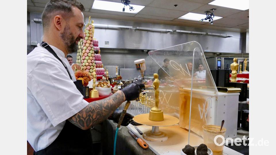 Der französische Konditor Garry Larduinat packt beim Vergolden mit an. Bild: Barbara Munker/dpa