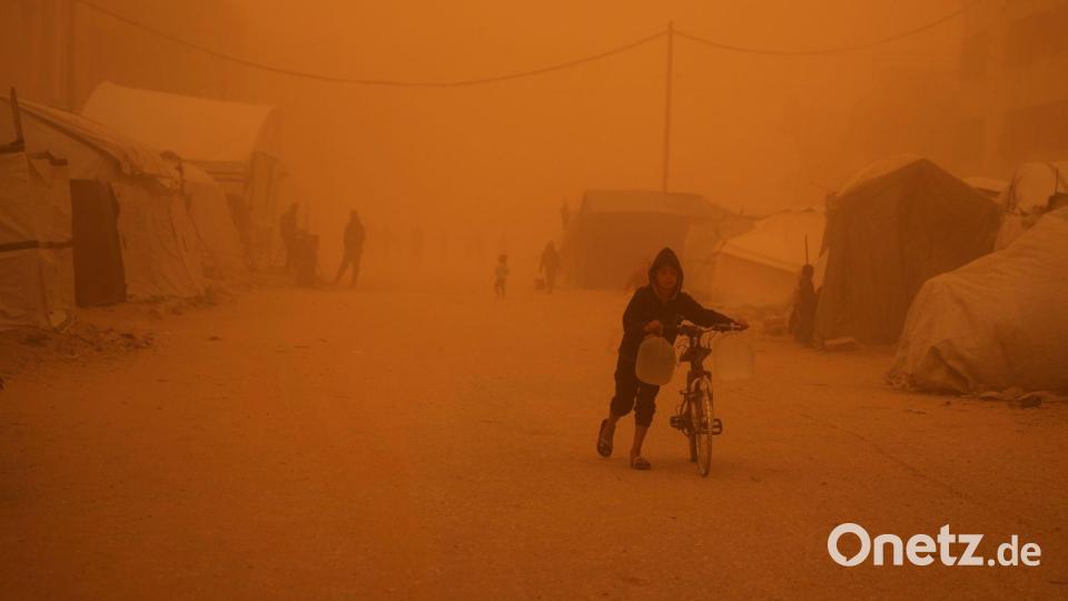 Ein Junge schiebt sein Fahrrad durch einen Sandsturm in Chan Junis. Bild: Abdel Kareem Hana/AP/dpa