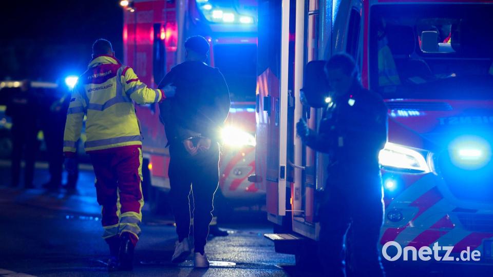 Ein Tatverdächtiger in Handschellen wird nach Schüssen in Mönchengladbach von einem Sanitäter zu einem Rettungswagen gebracht. Bild: Christoph Reichwein/dpa