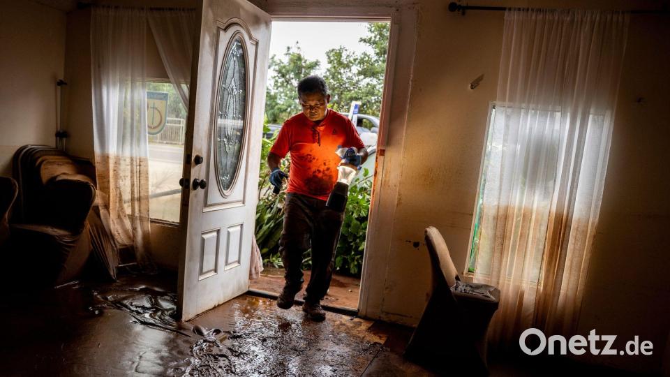 Glenn Duquez, stellvertretender Pastor der Church of God Jesus is Alive Fellowship, trägt eine Lampe in das schlammdurchtränkte Kirchengebäude, um nach der Flut aufzuräumen. Bild: Stephen Lam/San Francisco Chronicle via AP/dpa