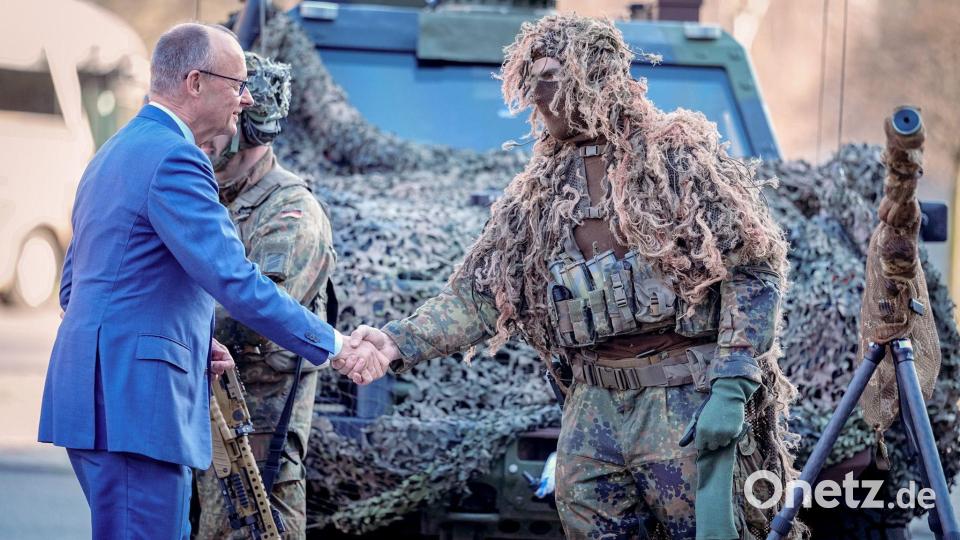 Bundeskanzler Friedrich Merz (l, CDU) wird bei der Verleihung des Fahnenbandes an das Wachbataillon in Berlin von einem Scharfschützen begrüßt. Bild: Kay Nietfeld/dpa