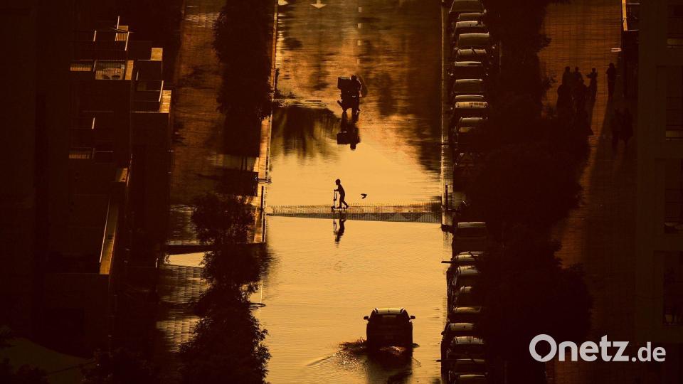 Ein Junge überquert eine mit Regenwasser gefüllte Straße in Schardscha, Vereinigte Arabische Emirate. Bild: Uncredited/AP/dpa