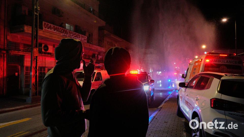 Anwohner beobachten die Arbeit der Rettungskräfte am Ort eines Raketeneinschlags in Tel Aviv. Bild: Maya Levin/AP/dpa