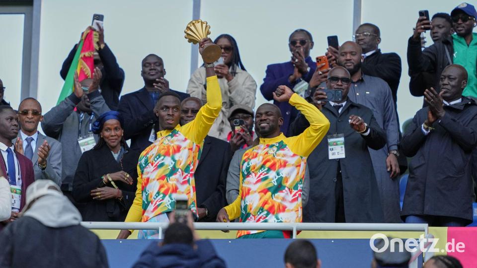 Senegalesische Spieler feiern mit der Afrika-Cup-Trophäe vor dem Spiel. Bild: Aurelien Morissard/AP/dpa