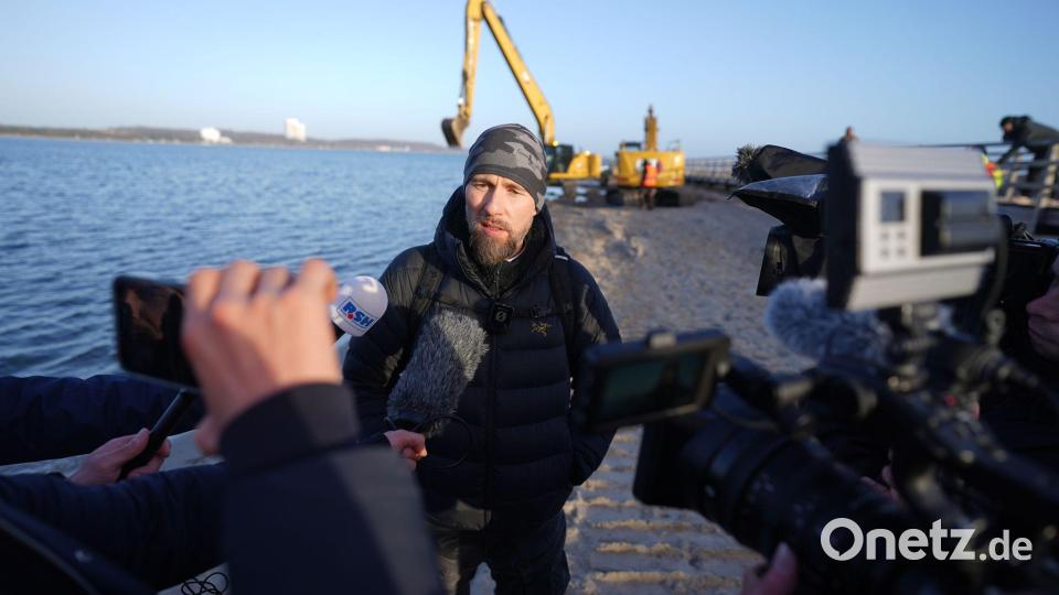 Robert Marc Lehmann spricht mit den Medien am Strand, in dessen Nähe der gestrandete Buckelwal im Wasser gelegen hatte. Bild: Marcus Brandt/dpa