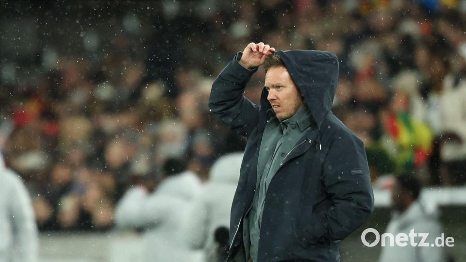 Julian Nagelsmann zieht sich im Regen eine Kapuze über den Kopf. Bild: Christian Charisius/dpa