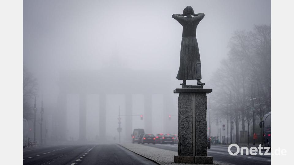 Schemenhaft ist das Brandenburger Tor im Nebel im Hintergrund der Bronzefigur „Der Rufer“ von Gerhard Marcks am frühen Morgen zu sehen. Bild: Kay Nietfeld/dpa