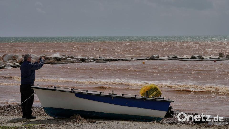 Ein Mann macht Fotos am Strand von Marathon, nachdem schwere Stürme über Nacht große Schäden verursacht haben. Bild: Thanassis Stavrakis/AP/dpa