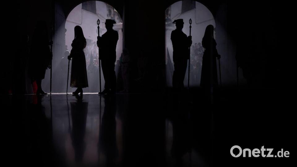 Ein Beamter der Guardia Civil (r) und ein Büßer nehmen an einer Prozession teil. Bild: Manu Fernandez/AP/dpa