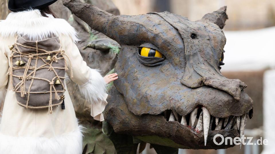 Eine Frau geht beim Mittelalterfest auf der Niederburg in Kranichfeld am Drachen Fangdorn vorbei. Am Karsamstag finden im Freistaat zahlreiche Veranstaltungen und Gottesdienste statt. Bild: Michael Reichel/dpa