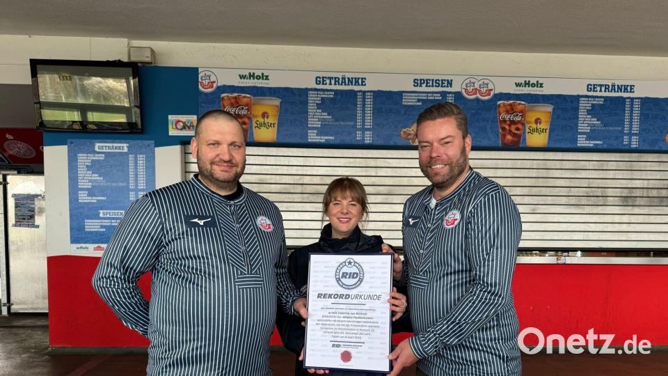 Das Catering-Team des Ostseestadions Rostock um Geschäftsführer Christoph Wulff (r) und Küchenchef Jens Schaumburg (l) hat das längste Fischbrötchen der Welt produziert. Bestätigt wurde der Rekord von Laura Koblischek (M) vom Rekord-Institut Deutschland. (Foto Handout) Bild: --/F.C. Hansa Rostock /dpa