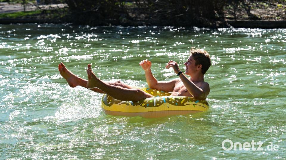 Julian treibt in einem aufblasbaren Donut im Eisbach im Englischen Garten in München. Bild: Malin Wunderlich/dpa