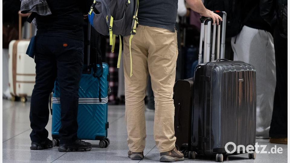 Passagiere stehen am Münchner Flughafen mit ihrem Gepäck an einem Check-in-Schalter. Bild: Sven Hoppe/dpa