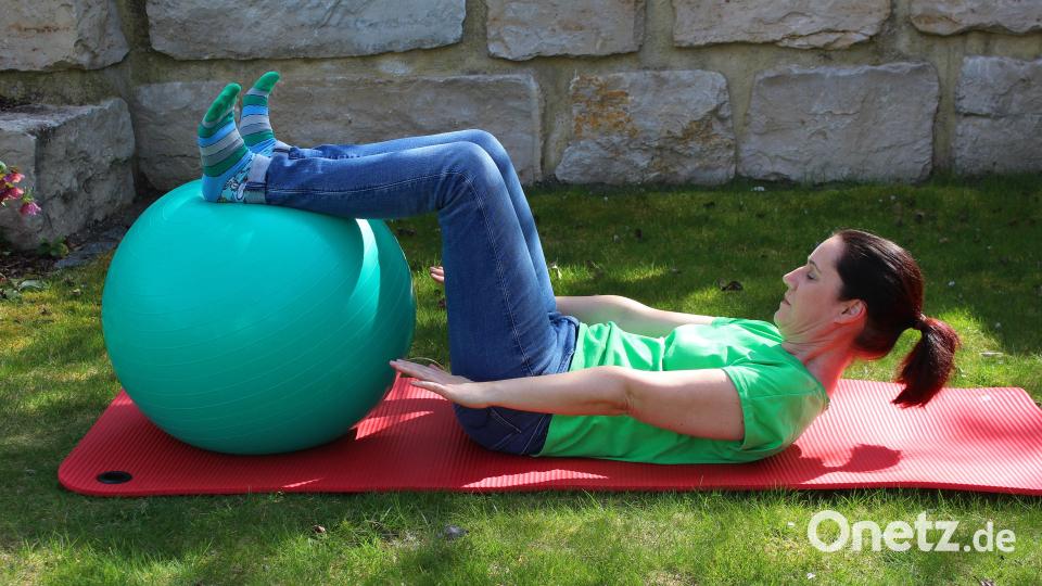 Füße auf den Ball legen, Fersen in den Ball drücken. Die Beine sind gebeugt. Jetzt Gesäß anspannen, Bauch einziehen, Oberkörper und Kopf anheben. Das Ganze etwa 15 Sekunden halten, die Übung drei- bis fünfmal wiederholen. Bild: Evi Wagner