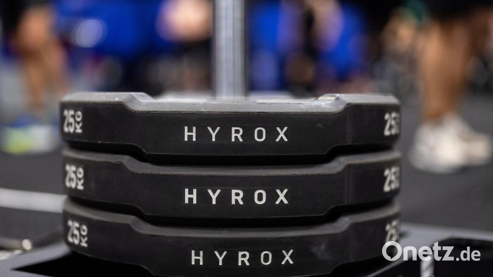 Hantelscheiben mit dem Schriftzug Hyrox an einem Messestand, wo wenig später ein Lauf- und Workout-Wettbewerb stattfinden sollte. Bild: Rolf Vennenbernd/dpa