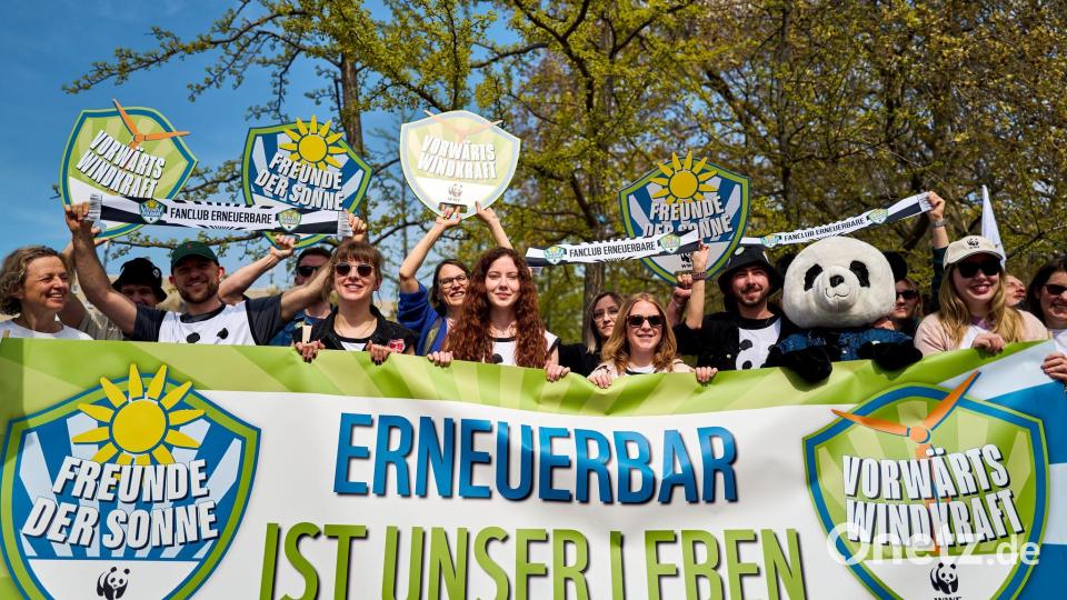 Demonstrierende halten ein Banner und Schilder in die Höhe, darunter eine Person im Pandakostüm. Bild: Michael Ukas/dpa