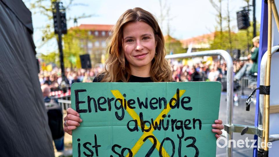 Luisa Neubauer hält ein Schild mit der Aufschrift „Energiewende abwürgen ist so 2013“ in der Hand. Bild: Michael Ukas/dpa