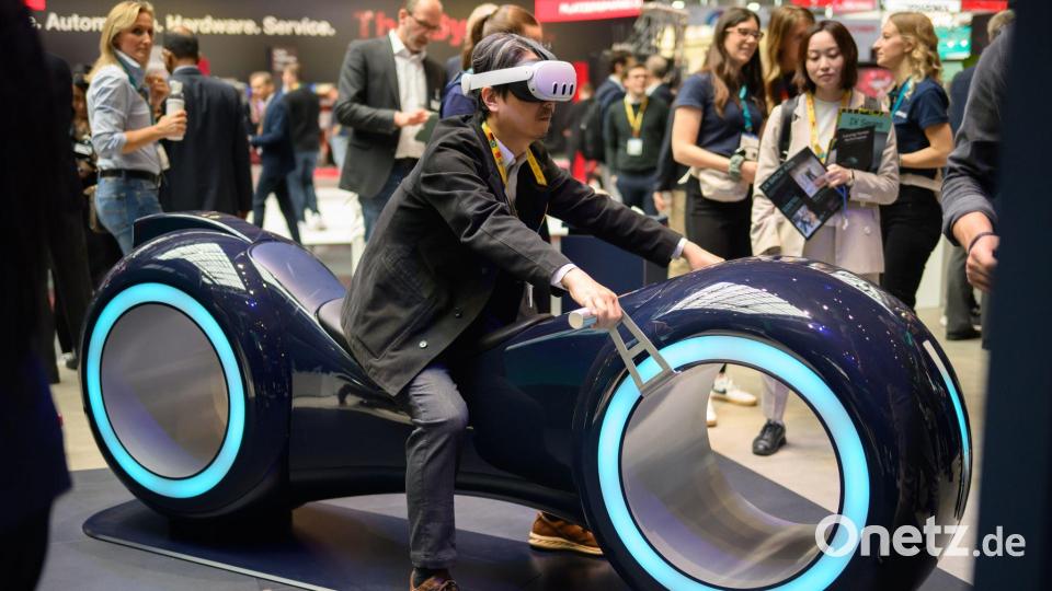 Durch eine Augmented-Reality-Brille schauend sitzt ein Gast auf einem fiktiven Gefährt bei der Industriemesse Hannover. Bild: Julian Stratenschulte/dpa