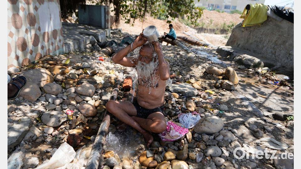 Ein heiliger Mann kühlt sich an einem heißen Tag in der indischen Stadt Jammu mit Wasser ab. Bild: Channi Anand/AP/dpa