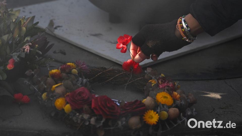 Eine Person legt eine Mohnblume an der Gedenkstätte "Für unser Land" während der Gedenkfeier für Aborigines und Torres-Strait-Insulaner (ATSIVA) im Rahmen des Anzac-Tags am Australian War Memorial in Canberra nieder. Bild: Lukas Coch/AAP/dpa